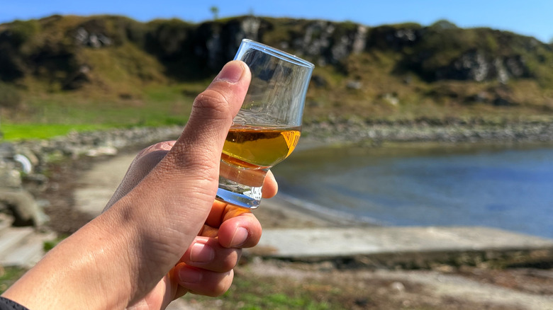A hand holding a glass of whisky on the Isle of Islay
