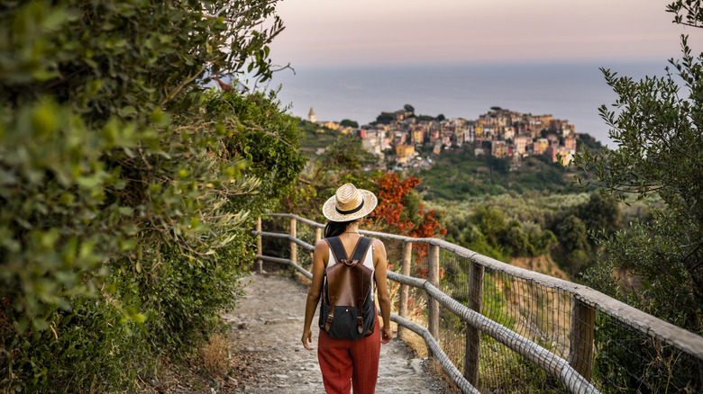 a person wearing an hat with backpack walking alongside a bridge